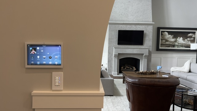 Control4 touchscreen mounted on wall with view into elegant living room