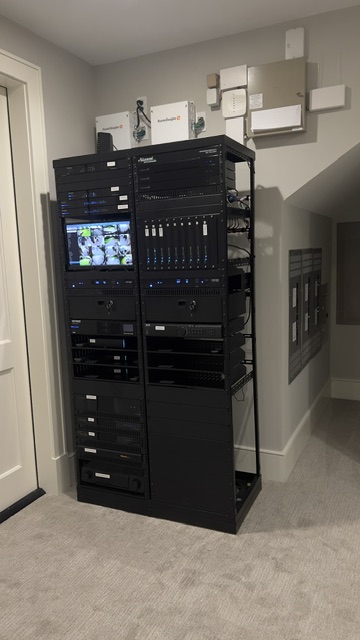 Large dual-bay AV equipment rack installed in home staircase alcove