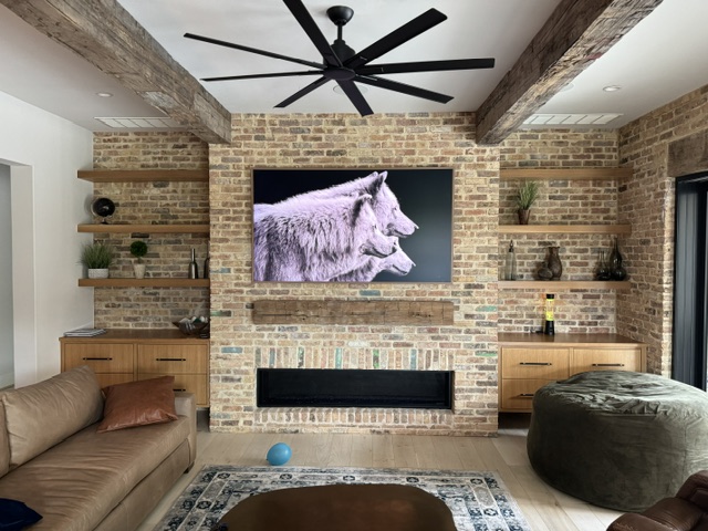 Large TV mounted on exposed brick wall with built-in shelving