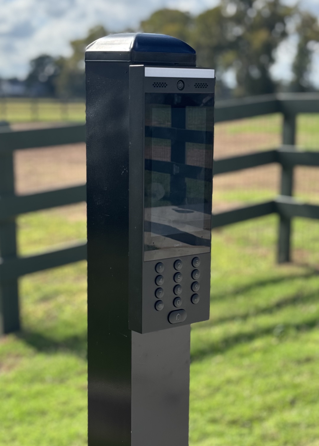 Close-up of gate video intercom with camera and keypad on black post